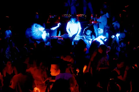Gray Contrast at his rig in blue light, seen from the gallery above a dancing crowd